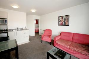 a living room with a red couch and a kitchen at Salerno Motel Apartments in Christchurch