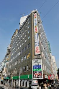 un edificio alto con letreros a un lado. en Kurashiki Station Hotel, en Kurashiki