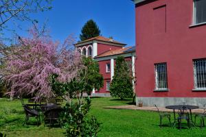un bâtiment rouge avec des tables et des chaises dans une cour dans l'établissement Agriturismo Tenuta Polledro, à Asti