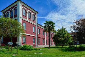 um edifício vermelho com uma palmeira em frente em Agriturismo Tenuta Polledro em Asti