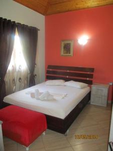 a bedroom with a large bed with a red wall at Vila Horizont Ksamil in Sarandë
