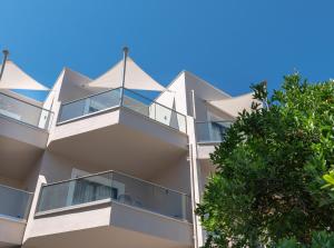 an apartment building with balconies and a tree at Eva Mare Hotel & Suites - Adults only in Agia Pelagia