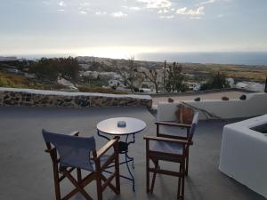 un patio con 2 sillas y una mesa con un ordenador portátil en Alonistra Oia Houses, en Oia