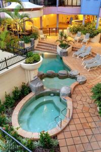 a swimming pool in a building with chairs around it at Nautilus Resort Mooloolaba in Mooloolaba