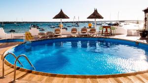 a large swimming pool with chairs and tables at FORMENTERADREAMING SUITe in La Savina