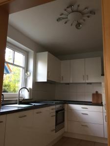 a kitchen with white cabinets and a ceiling fan at Meeresbrise in Graal-Müritz +9 photos