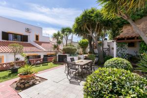 a patio with a table and chairs and palm trees at 3 Marias Garden House B&B in Lagos