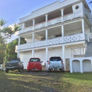 dos autos estacionados frente a un edificio blanco en Harbour Vista Inn en Castries