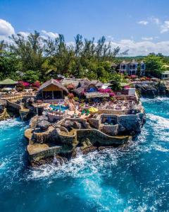 a resort on the water with chairs and tables at Catcha Falling Star in Negril