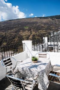 een tafel en stoelen op een balkon met uitzicht bij Apartamentos Vista Veleta in Capileira