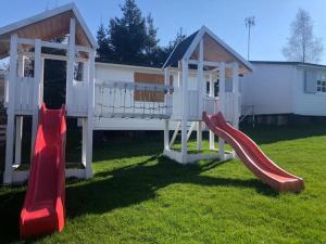 um parque infantil com dois escorregas na frente de uma casa em STAŁY LĄD em Ustronie Morskie