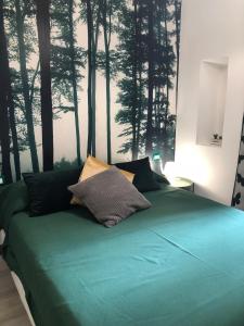 a bedroom with a green bed with trees on the wall at giolitti central room in Rome