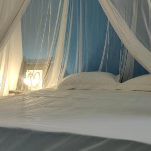 1 cama con dosel y almohadas blancas en Escale Caraibes, en Trois-Rivières