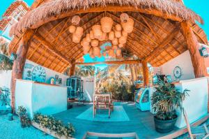 a building with a thatched roof with a table and chairs at Ensueño Holbox & Beach Club in Holbox Island