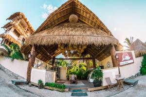 domek ze słomianym dachem, stołem i krzesłami w obiekcie Ensueño Holbox & Beach Club w mieście Isla Holbox