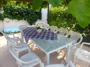 a table with white chairs and a table with a platter on it at Kostalina Hotel Studios in Limenas
