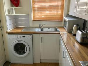 a kitchen with a washing machine and a sink at Vinery House in Leeds