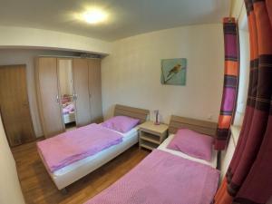 two beds in a room with pink sheets at Apartment Ana in Poreč