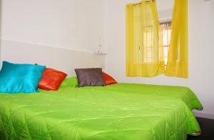 ein grünes Bett mit bunten Kissen darüber in der Unterkunft Playa centro in Villajoyosa