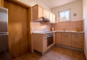 eine kleine Küche mit Holzschränken und einem Fenster in der Unterkunft Apartmani Čvorak in Vodice