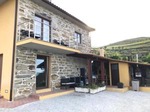 ペーゾ・ダ・レーグアにあるCasa do Coelhalのバルコニーとパティオ付きの石造りの家
