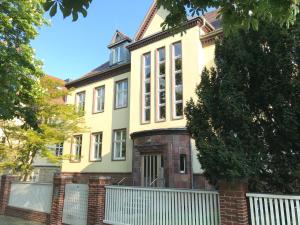 uma casa amarela com uma cerca branca à frente. em Ferienwohnungen und Apartmenthaus Halle Saale - Villa Mathilda em Halle an der Saale