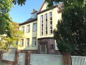 a yellow house with a white fence in front of it at Ferienwohnungen und Apartmenthaus Halle Saale - Villa Mathilda in Halle an der Saale