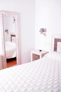 Habitación blanca con 2 camas y espejo. en Apartamentos Vista Veleta en Capileira