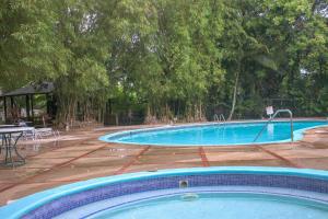 une grande piscine avec une table et des arbres dans l'établissement Log 33, à Ocho Rios