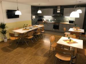 una cocina con mesas y sillas en una habitación en Ferienwohnungen und Apartmenthaus Halle Saale - Villa Mathilda, en Halle an der Saale