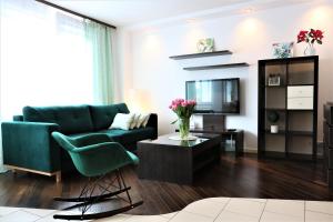 ワルシャワにあるStylish and spacious by Cooee Apartmentsのリビングルーム(緑のソファ、テレビ付)