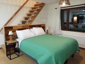 a bedroom with a green bed and a staircase at Casa Río Vivo in Valdivia