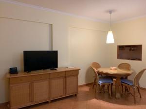 a living room with a table and a television on a cabinet at Cabanas de Tavira Apartment in Cabanas de Tavira