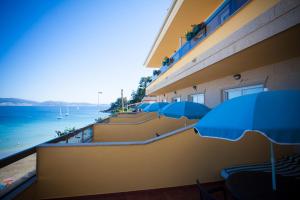 a building with blue umbrellas next to the ocean at Hotel Martín Esperanza in Portonovo