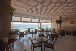 a restaurant with tables and chairs and a view of the ocean at Hotel Martín Esperanza in Portonovo