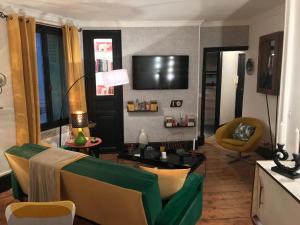 een woonkamer met een bank en een tv bij LA RIEUSE POUET-POUET in Mers-les-Bains