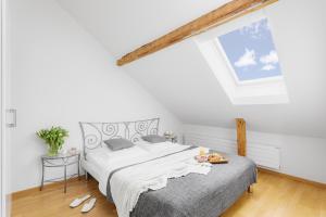 a white bedroom with a bed and a skylight at Swiss Star Marc Aurel - Self Check-In in Zurich