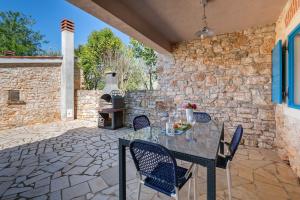 a patio with a table and chairs and a stone wall at Studio Q in Fažana