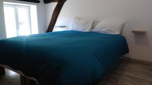 a bed with a blue blanket and a white pillow at JOLIE MAISON AVEC JARDIN PRIVE DANS LE CENTRE VILLE DE BRIARE in Briare