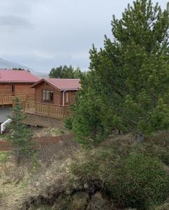 uma casa de madeira com um deque e árvores em Cosy cottage-Golden circle em Kerhraun