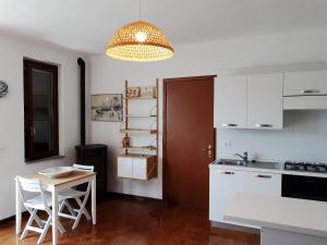 une cuisine avec des placards blancs, une table et un lustre dans l'établissement Nisportino, à Rio nellʼElba