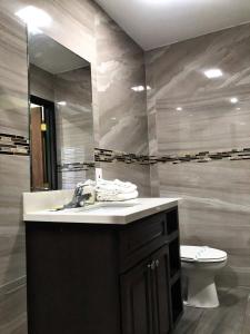 Un baño con lavabo, inodoro y espejo. en Central Inn Motel, en Los Ángeles