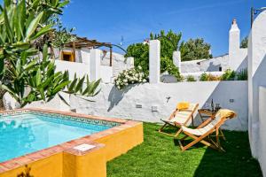 a backyard with a swimming pool and chairs and a house at Casa de Veiros - Estremoz in Estremoz