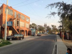 une rue vide avec des voitures garées sur le côté d'un bâtiment dans l'établissement Hotel Lienzo Charro II, à San Miguel Regla