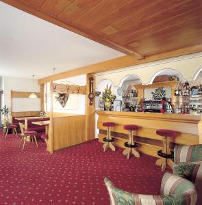 a restaurant with a bar and a table and chairs at Hotel Olympia in Molveno