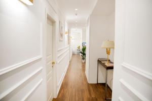a hallway with white walls and a table with a lamp at Unicum Roma Suites in Rome