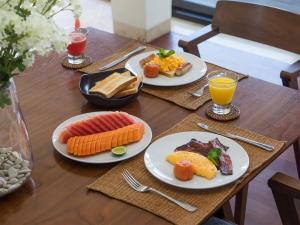 una mesa de madera con platos de comida y bebida en Villa Adenium by Elite Havens, en Jimbaran