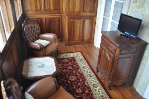 a living room with a tv and a chair and a table at Casa Manuel Espregueira e Oliveira in Viana do Castelo