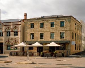 a building with tables and umbrellas in front of it at Moss Hotel in Hobart