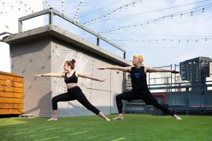 two women are doing yoga on the grass at MEANDER Taipei in Taipei